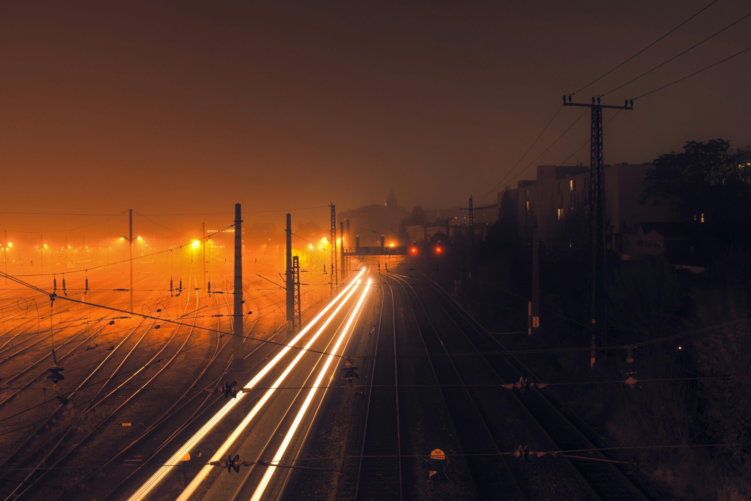 Long exposure photo of a foggy railway at night in Vienna with vibrant light trails.
